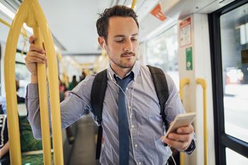 Man dressed professionally on a bus while on his cell phone at Pinecrest Apartments, California, 95616